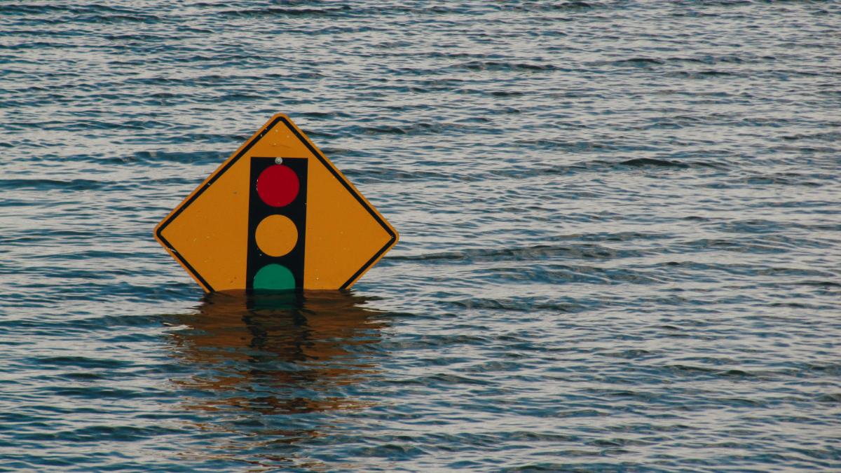 Cartello stradale sommerso dall'acqua durante un'alluvione: polizza catastrofale obbligatoria per le imprese